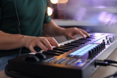 Photo of Man working with MIDI keyboard at table indoors, closeup
