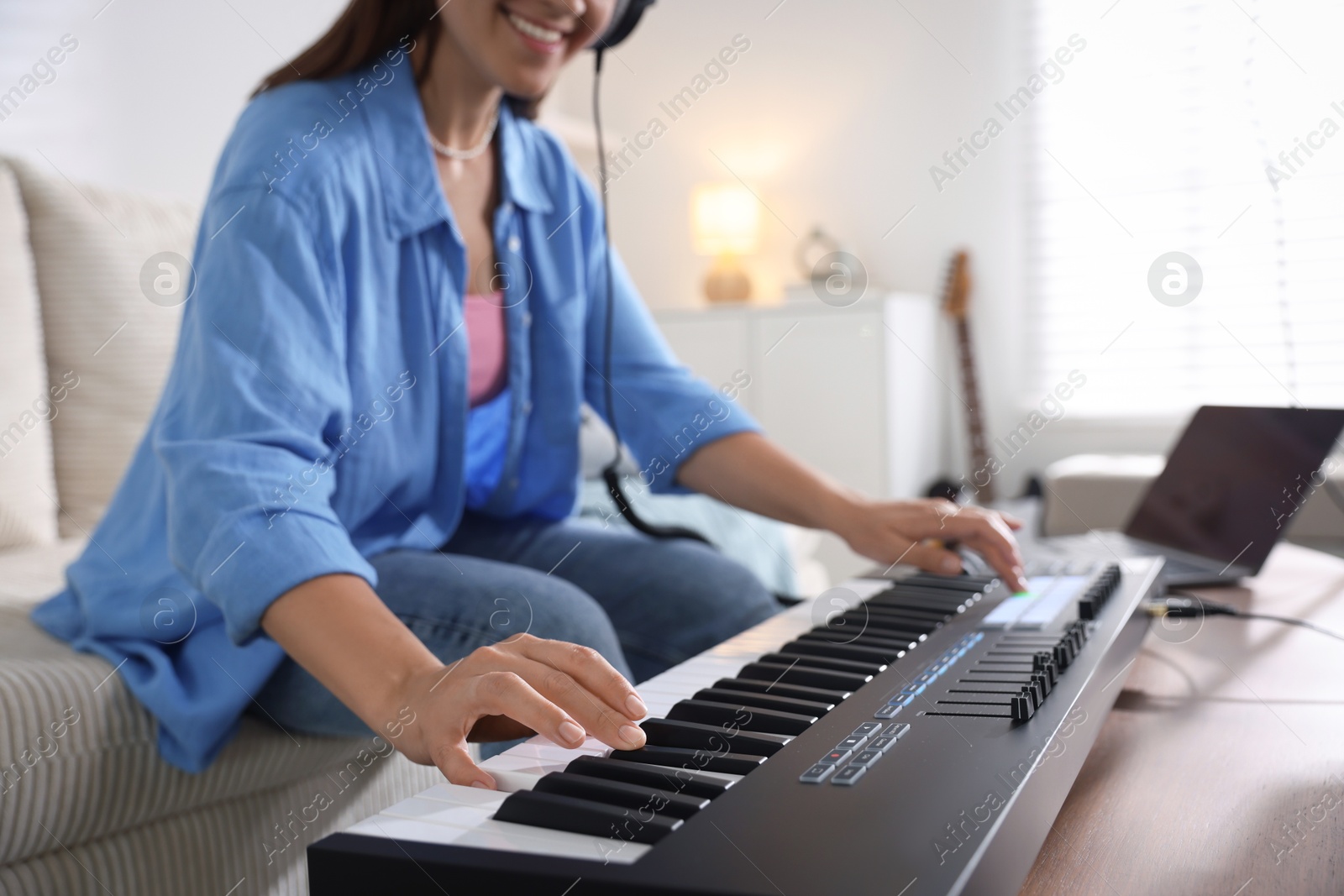 Smiling woman working with MIDI keyboard at table in home studio, closeup Photo of Smiling woman working with MIDI keyboard at table in home studio, closeup