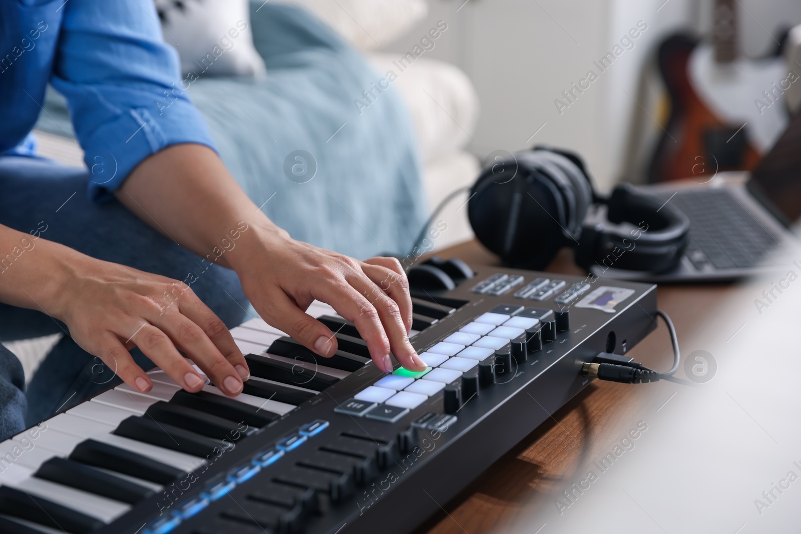 Photo of Woman working with MIDI keyboard at table indoors, closeup