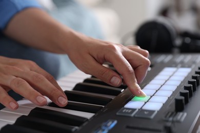 Photo of Woman working with MIDI keyboard indoors, closeup