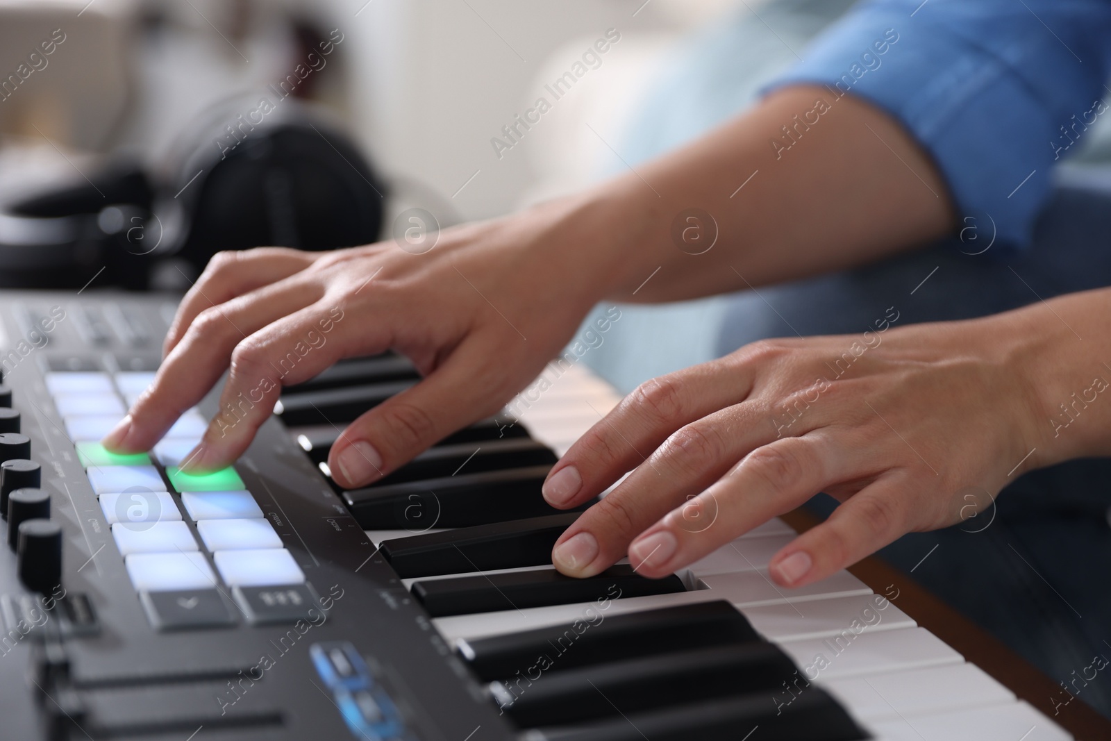 Photo of Woman working with MIDI keyboard indoors, closeup