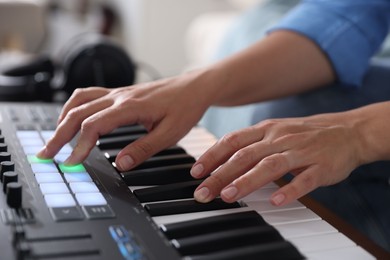 Photo of Woman working with MIDI keyboard indoors, closeup