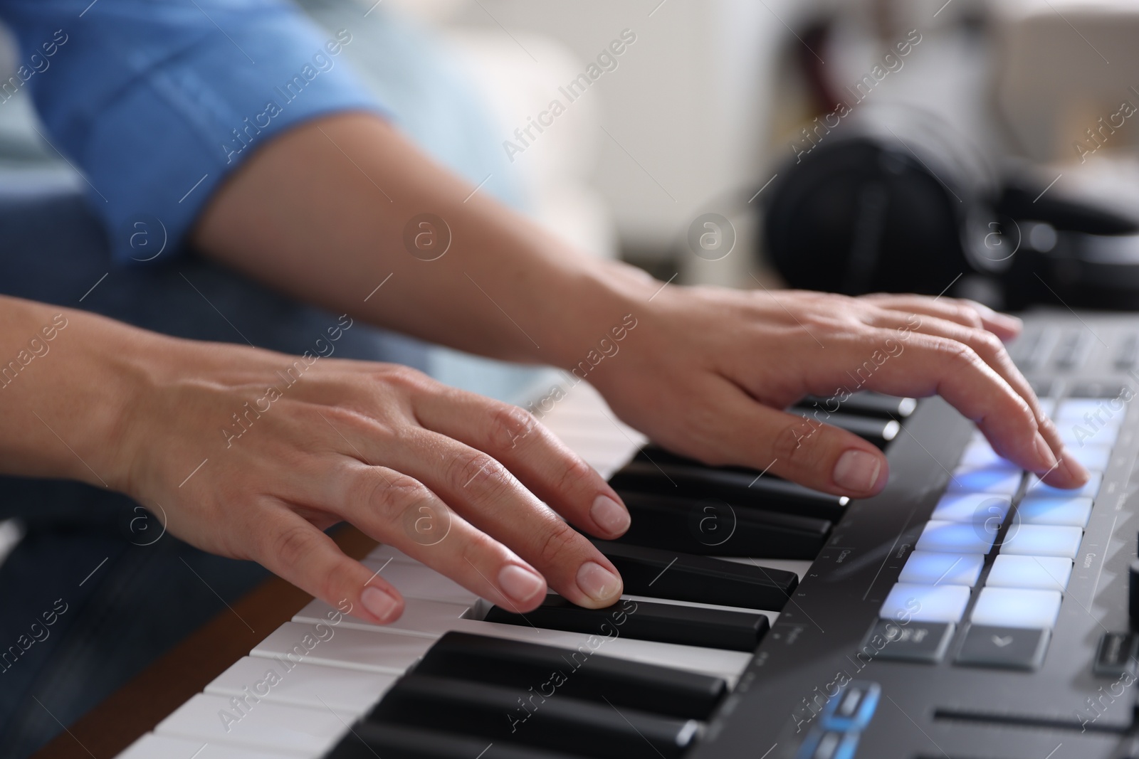 Photo of Woman working with MIDI keyboard indoors, closeup