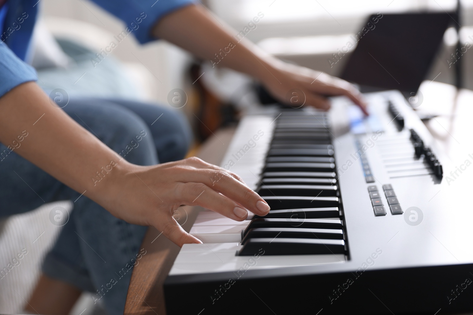 Photo of Woman working with MIDI keyboard at table indoors, closeup