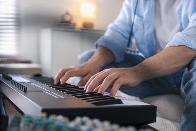 Photo of Man working with MIDI keyboard indoors, closeup