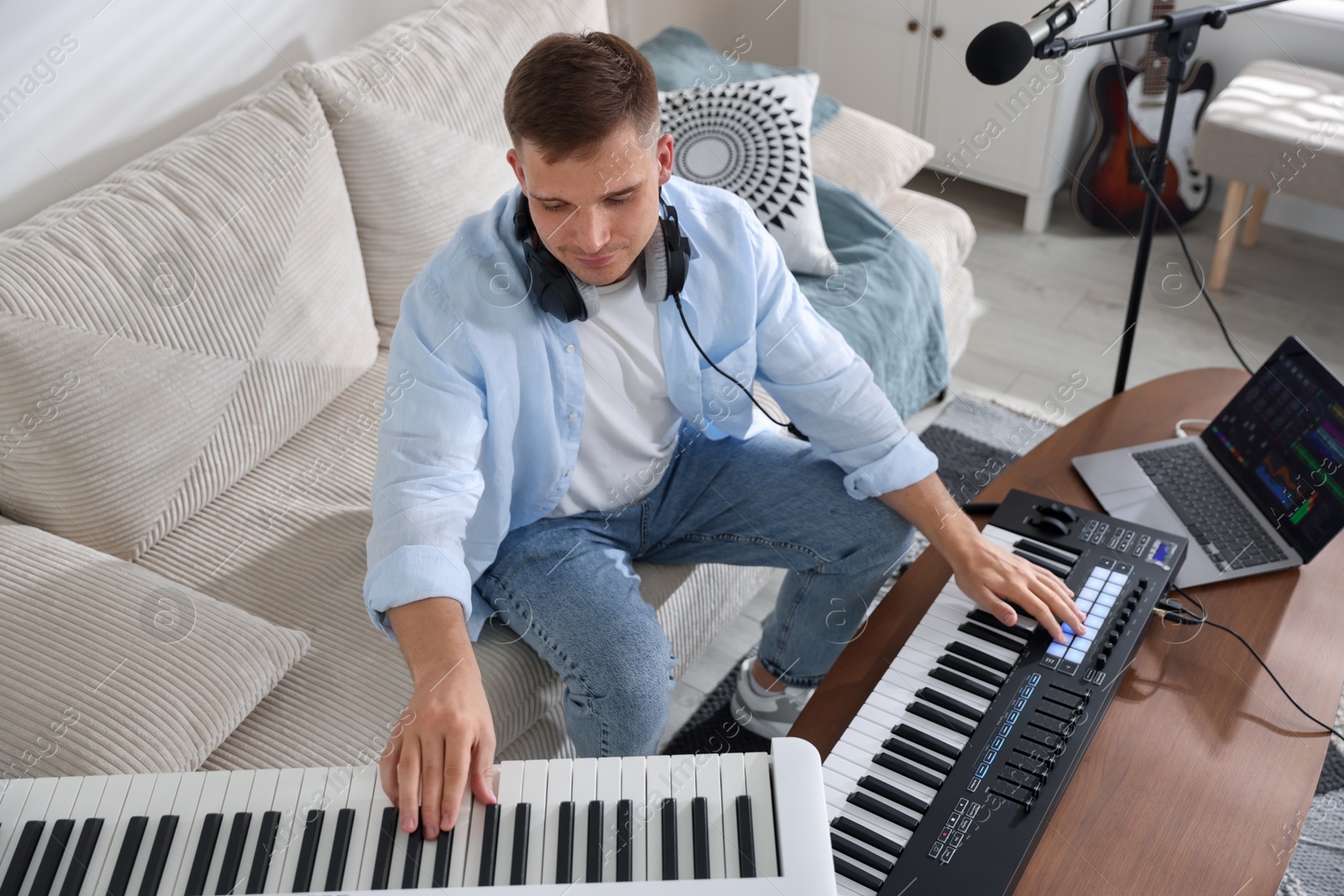 Photo of Man working with digital piano and MIDI keyboard in home studio
