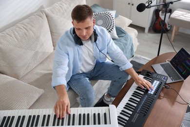 Photo of Man working with digital piano and MIDI keyboard in home studio