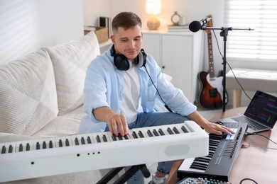 Photo of Man working with digital piano and MIDI keyboard in home studio