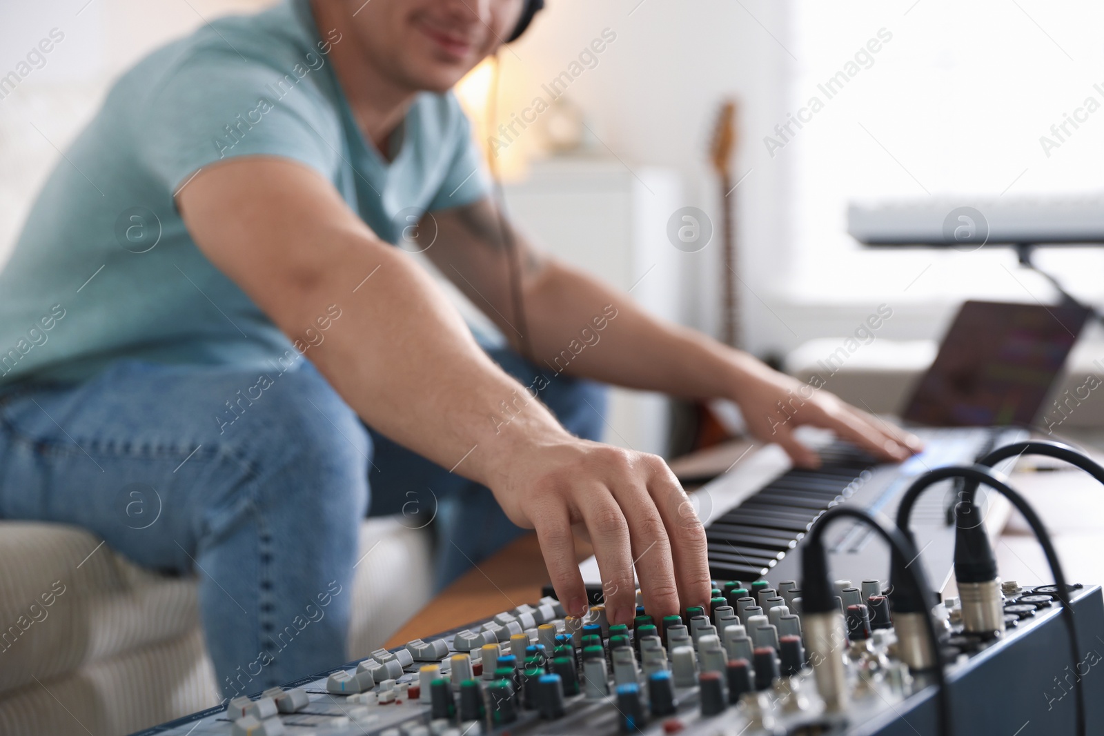 Photo of Man working with dj mixer and MIDI keyboard indoors, selective focus