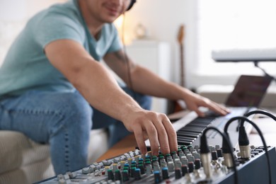Photo of Man working with dj mixer and MIDI keyboard indoors, selective focus