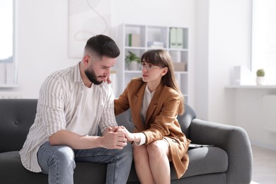 Photo of Psychologist supporting patient during therapy session on sofa in office