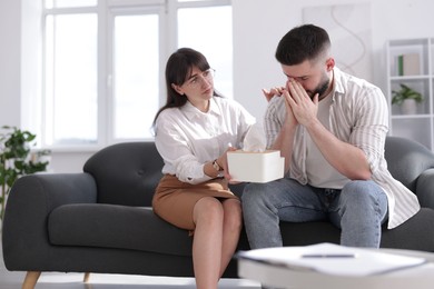 Photo of Psychologist supporting patient during therapy session on sofa in office