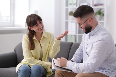 Photo of Professional psychologist working with patient on sofa in office