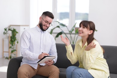 Photo of Professional psychologist working with patient on sofa in office