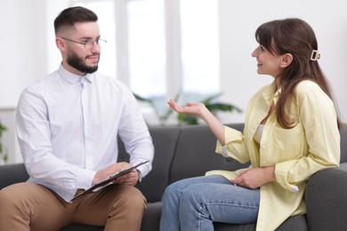 Photo of Professional psychologist working with patient on sofa in office