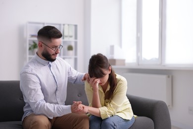 Photo of Psychologist supporting patient during therapy session on sofa in office