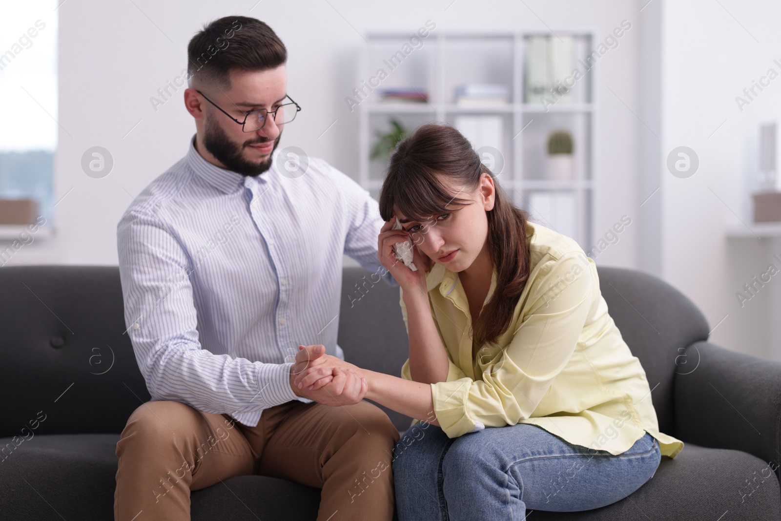 Photo of Psychologist supporting patient during therapy session on sofa in office