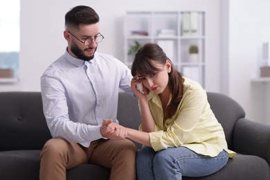 Photo of Psychologist supporting patient during therapy session on sofa in office