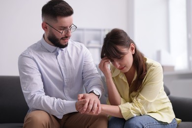 Photo of Psychologist supporting patient during therapy session on sofa in office