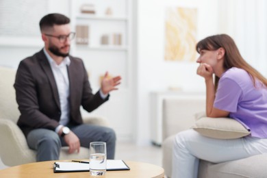 Photo of Professional psychologist working with patient in office, focus on glass of water