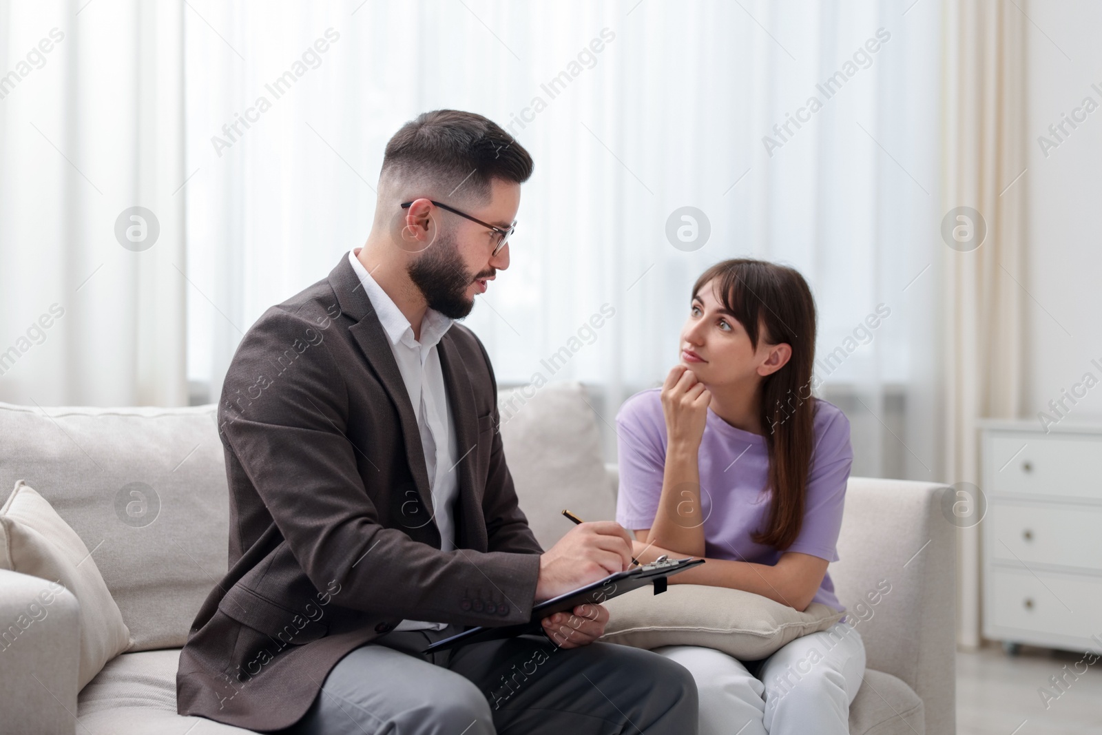 Photo of Professional psychologist working with patient on sofa in office