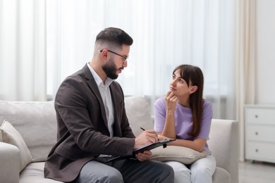 Photo of Professional psychologist working with patient on sofa in office