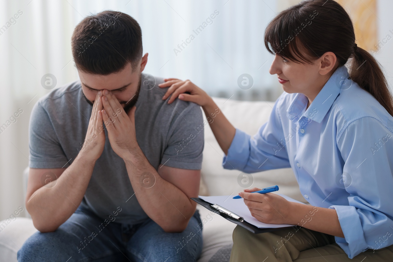 Photo of Psychologist supporting patient during therapy session on sofa in office