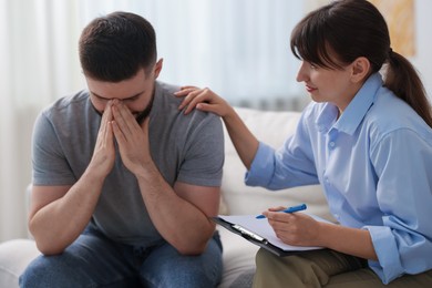 Photo of Psychologist supporting patient during therapy session on sofa in office