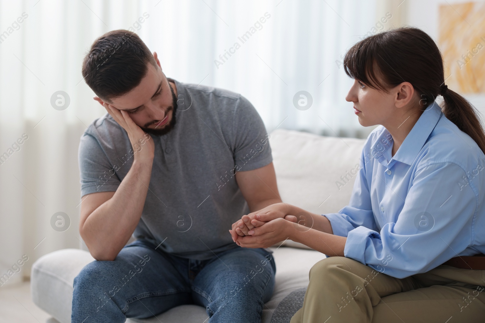 Photo of Psychologist supporting patient during therapy session on sofa in office