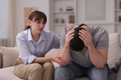 Photo of Psychologist supporting patient during therapy session on sofa in office