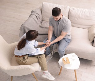 Photo of Psychologist supporting patient during therapy session in office, above view