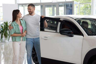 Photo of Happy family near new car in salon