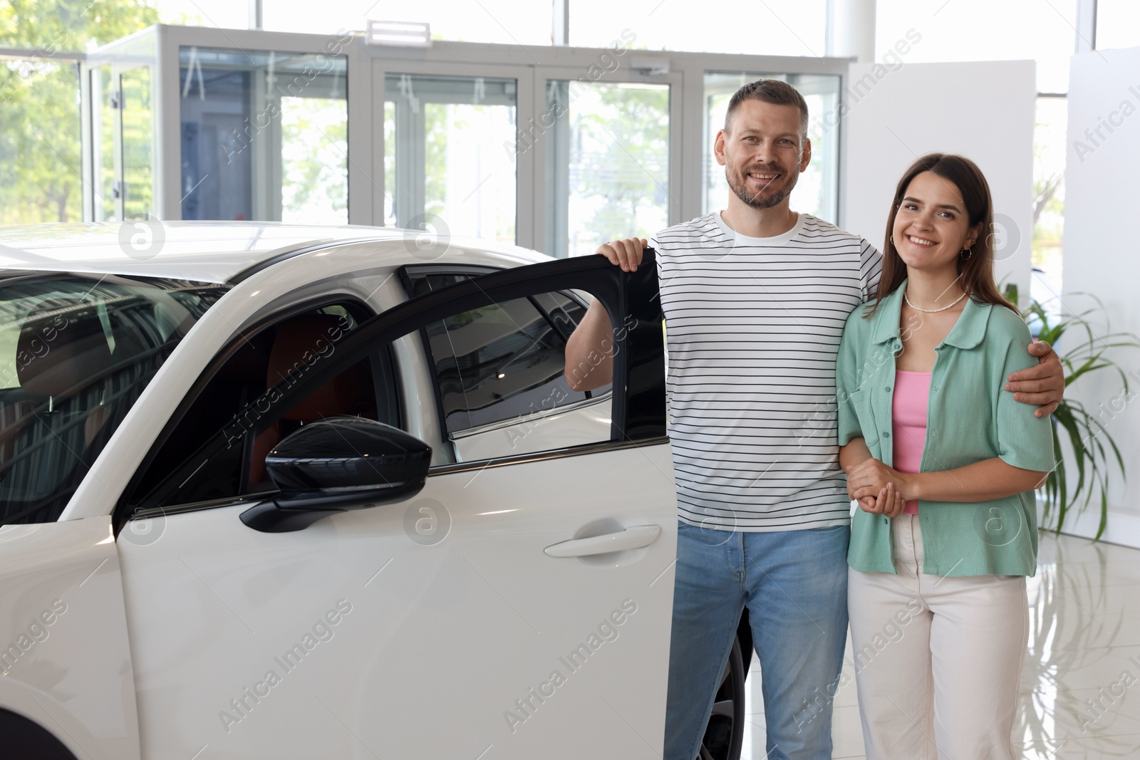 Photo of Happy family near new car in salon