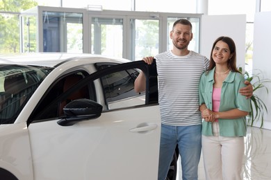 Photo of Happy family near new car in salon