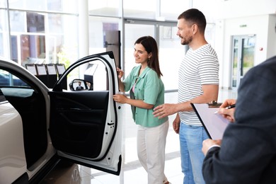 Photo of Salesman with clipboard showing new car to happy family in salon, closeup