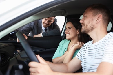 Photo of Salesman showing new car to happy family