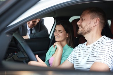 Photo of Salesman showing new car to happy family, selective focus