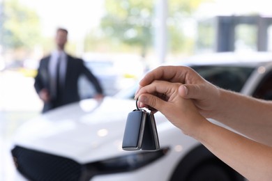 Photo of Family with car keys and salesman in salon, selective focus