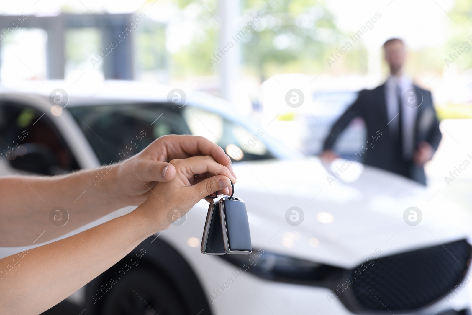 Photo of Family with car keys and salesman in salon, selective focus