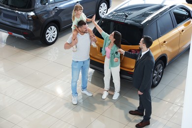 Photo of Salesman giving car key to happy family in salon