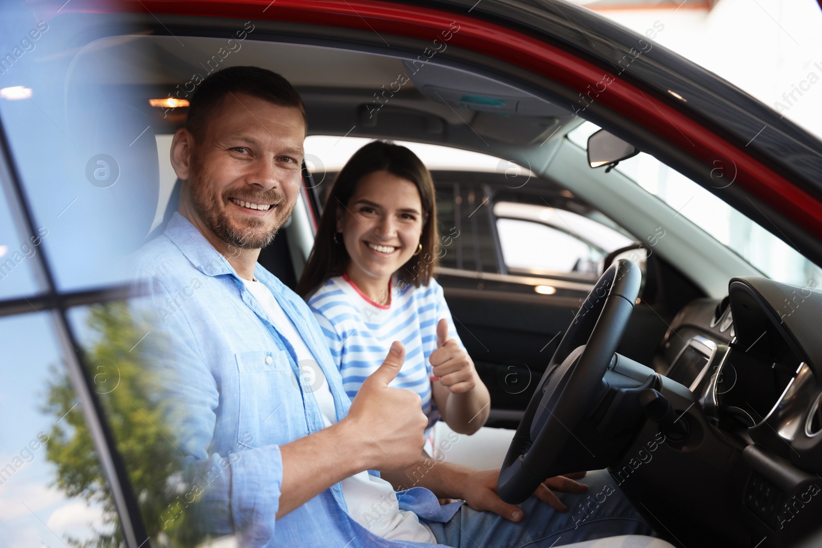 Photo of Happy family showing thumbs up inside new car