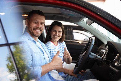 Photo of Happy family showing thumbs up inside new car