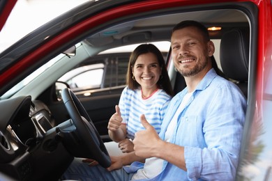 Photo of Happy family showing thumbs up inside new car