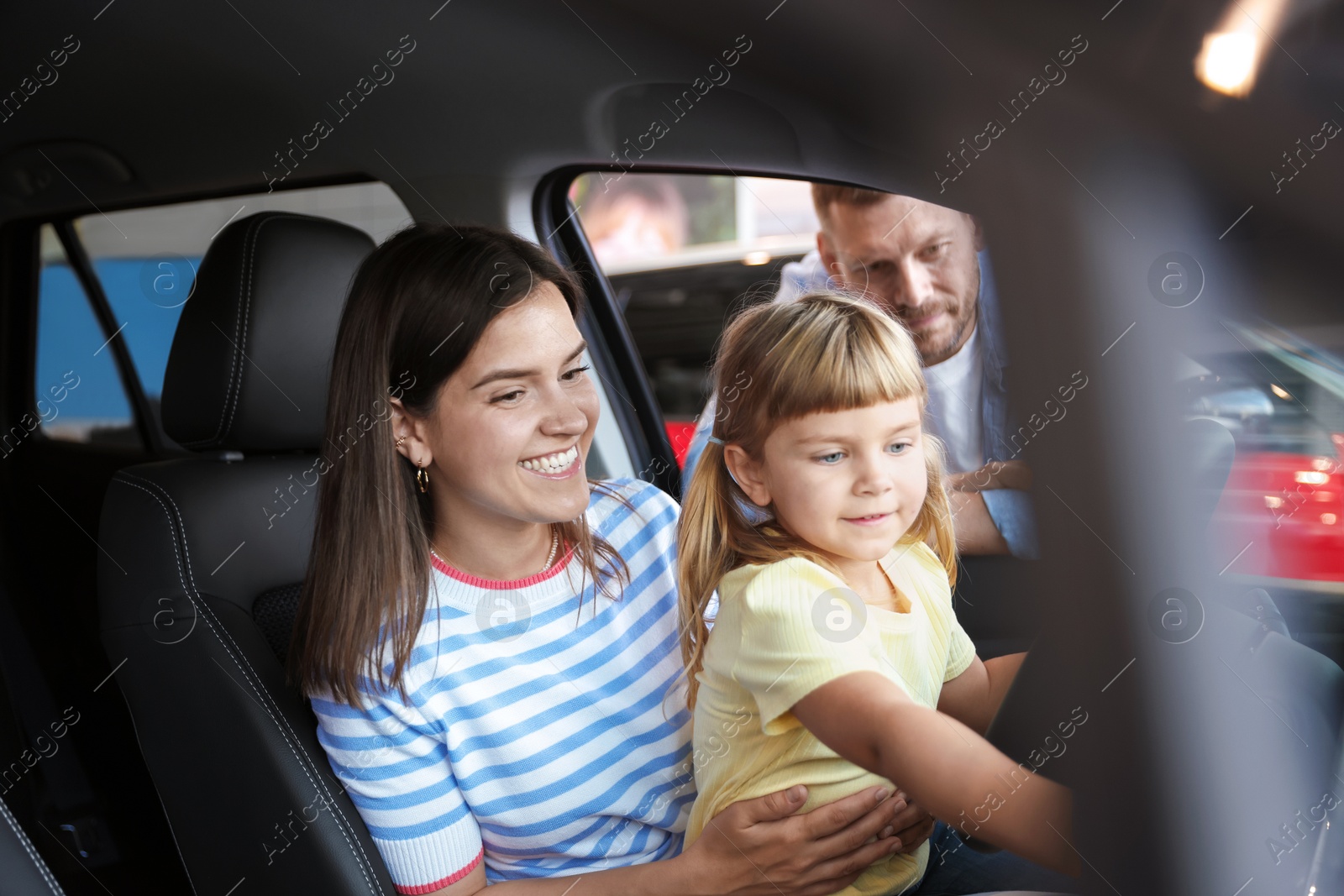 Photo of Happy family sitting inside new car. Luxury vehicle
