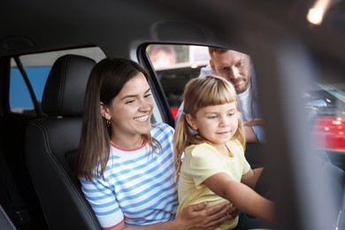 Photo of Happy family sitting inside new car. Luxury vehicle