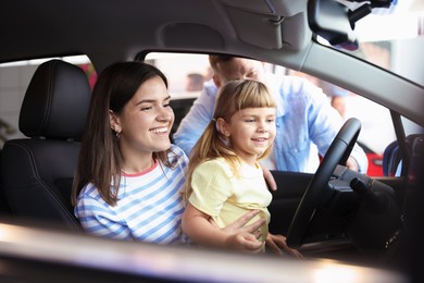 Photo of Happy family sitting inside new car. Luxury vehicle