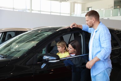 Photo of Happy family and new car in salon