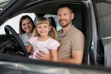 Photo of Happy family sitting inside new car. Luxury vehicle