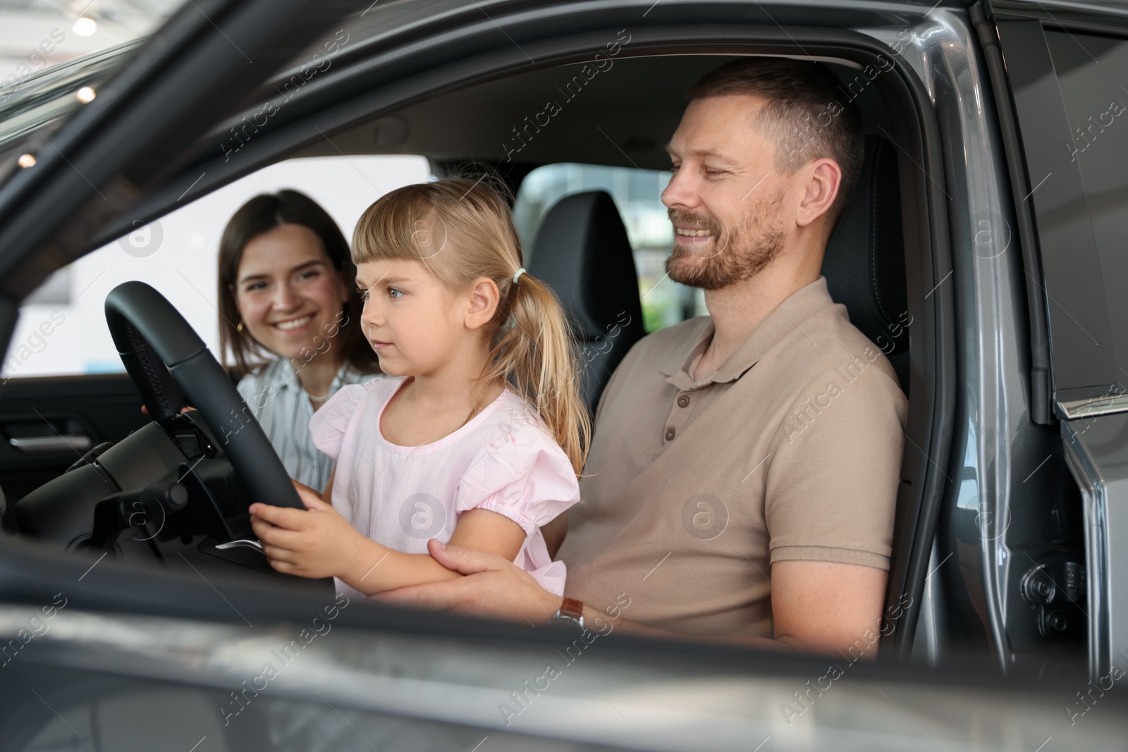 Photo of Happy family sitting inside new car. Luxury vehicle