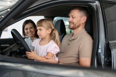 Photo of Happy family sitting inside new car. Luxury vehicle